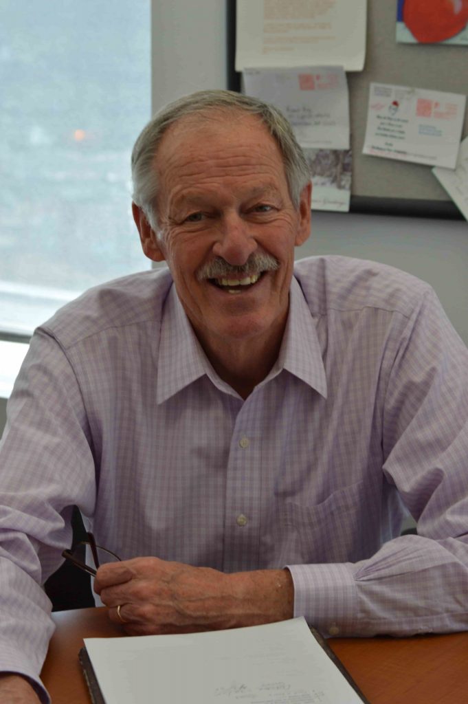 former FamilyAid Boston President Richard sitting at desk smiling