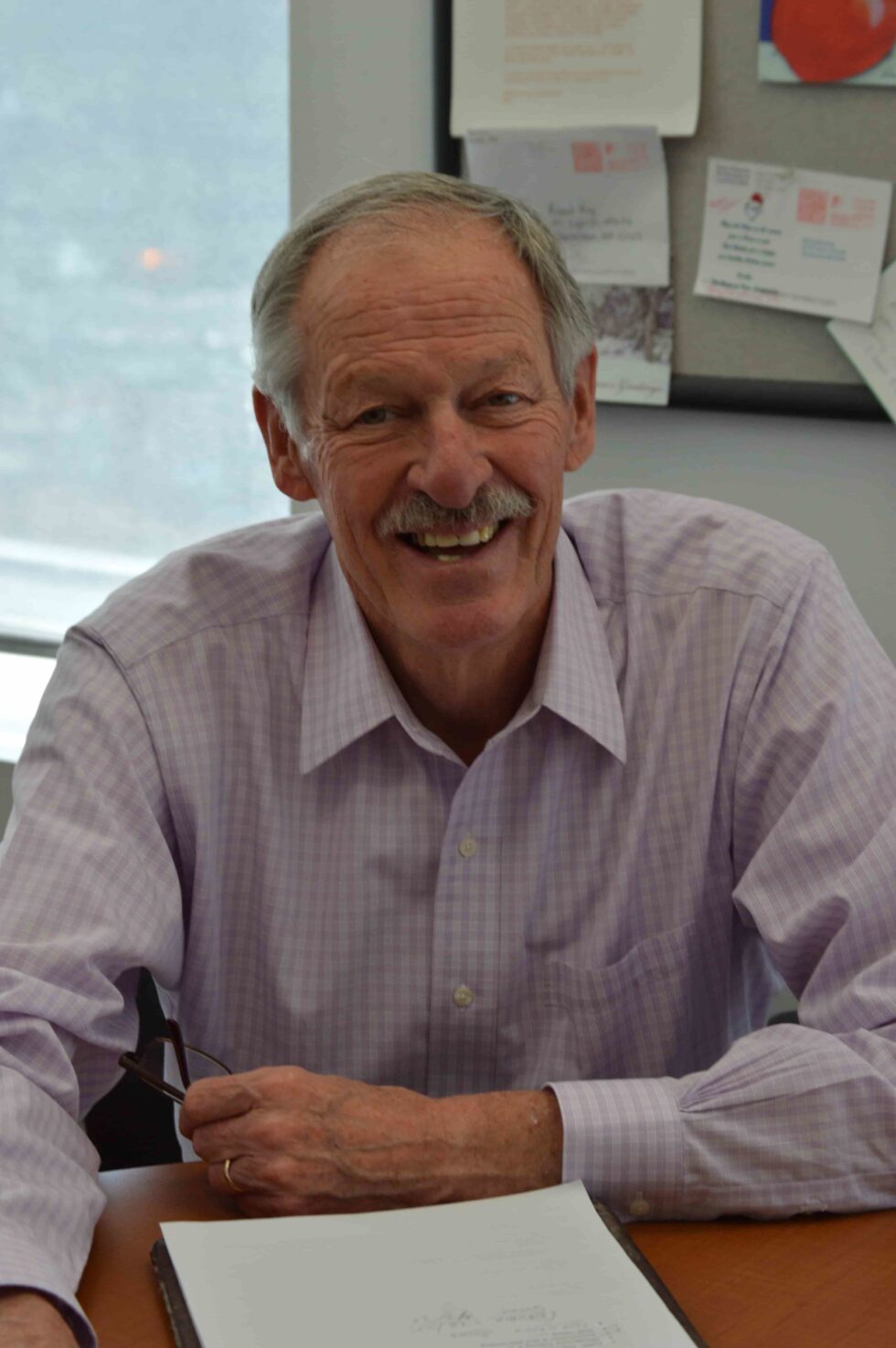 former FamilyAid Boston President Richard sitting at desk smiling