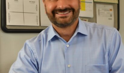 Smiling FamilyAid Boston president sitting at a desk wearing a blue button down shirt