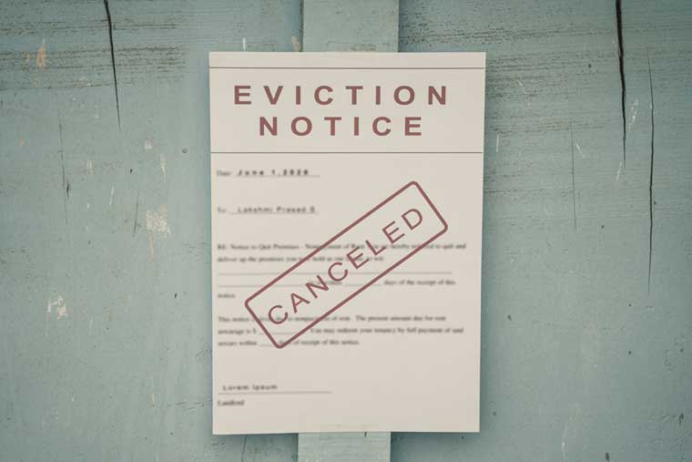 Photo of an eviction notice on a door with a cancelled stamp on it