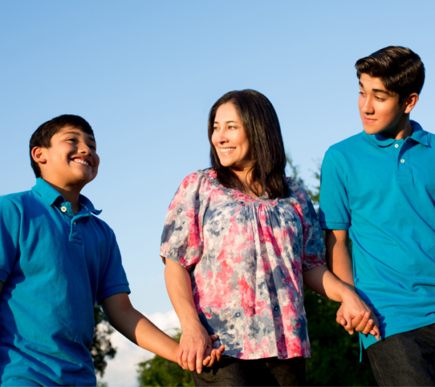 Mom with two sons smiling outside