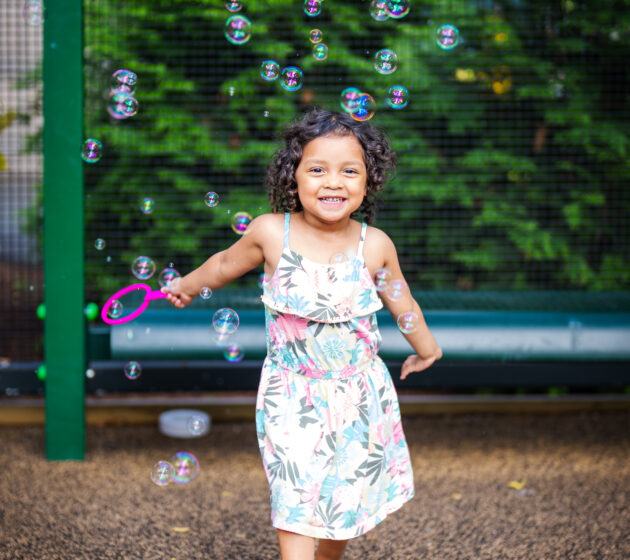 Little girl running through bubbles on a playground