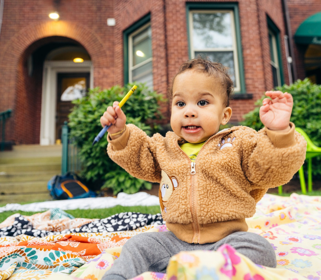 A small child plays with crayons outside