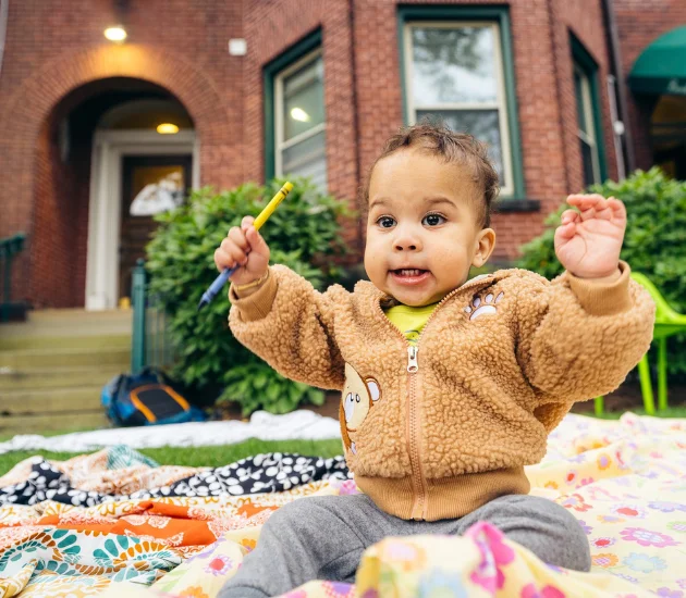 A small child plays with crayons outside