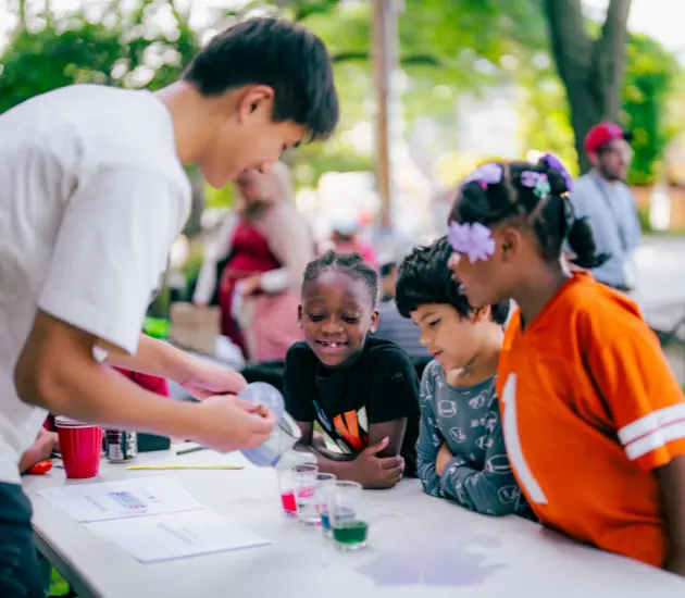 Children learn science outside with a volunteer
