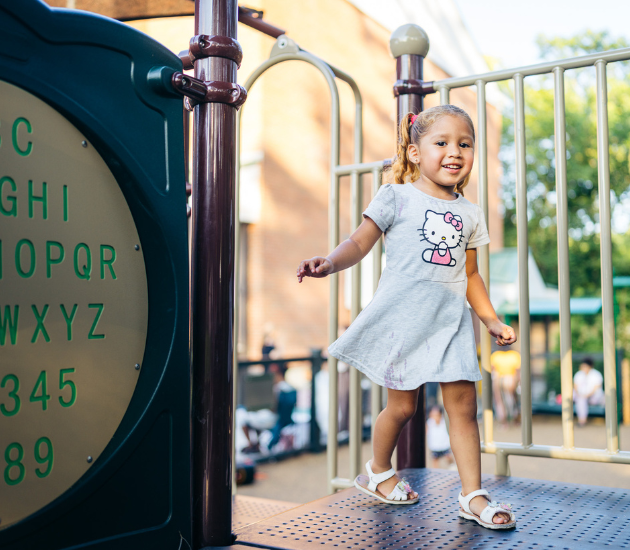 a young girl smiles on a playset